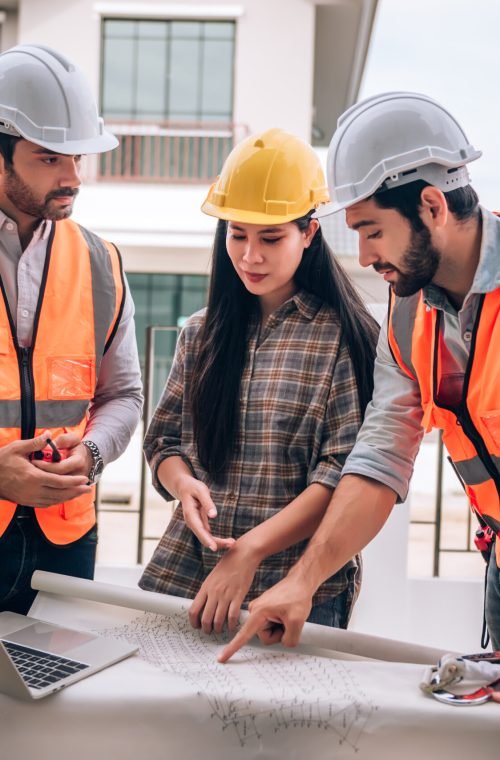 Civil engineer , Construction worker and Architects wearing hardhats and safety vests are working together at construction site ,building ,home in cooperation teamwork concept.